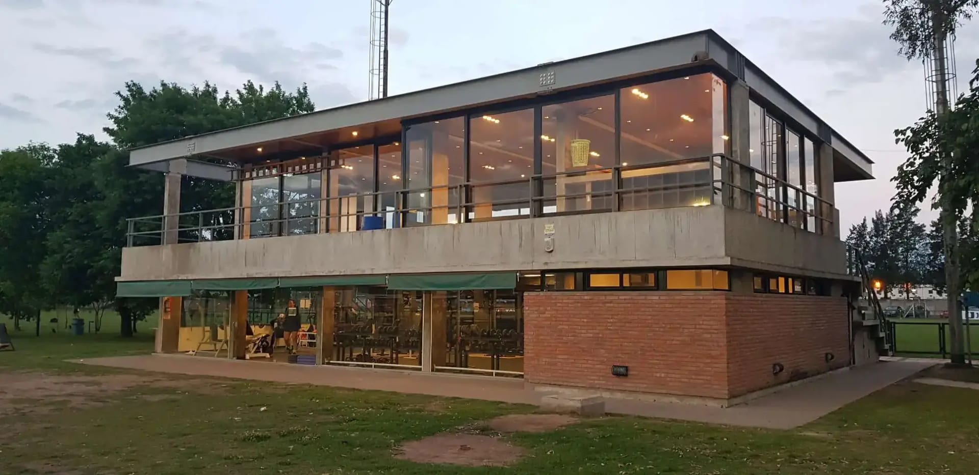 El edificio social del club al atardecer, con las luces encendidas