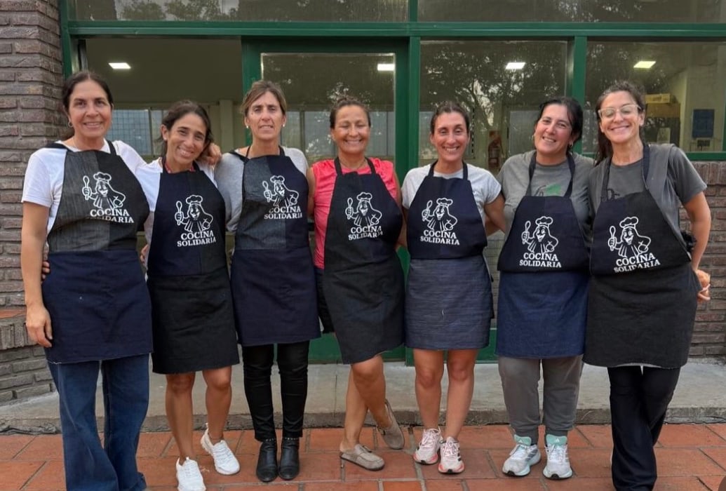 Equipo de voluntarias de Cocina Solidaria posando con sus delantales frente al club