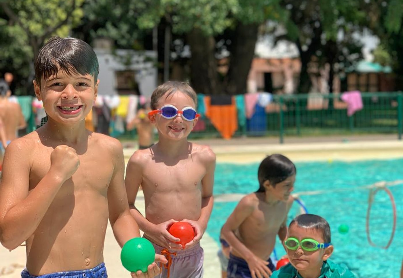 Chicos sonriendo con pelotas en la pileta del club