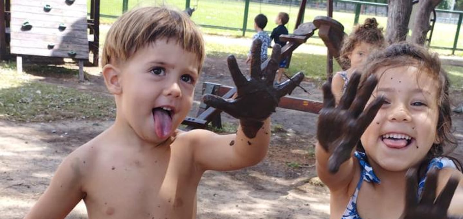 Dos chicos riendo con las manos llenas de barro